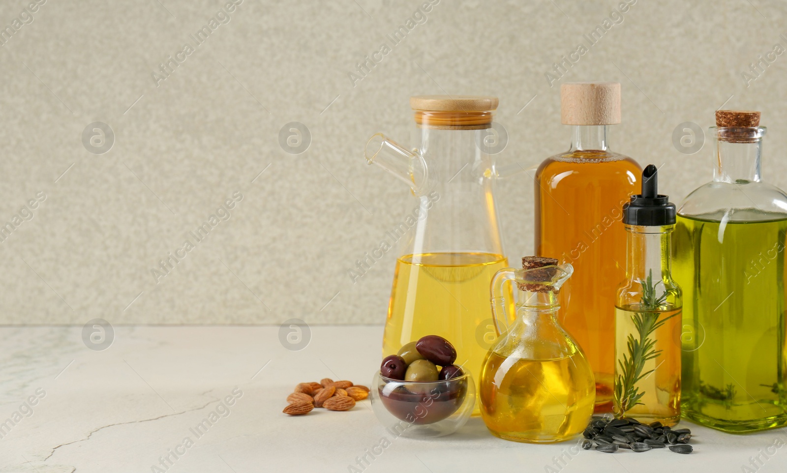 Photo of Vegetable fats. Different cooking oils in glass bottles and ingredients on white table, space for text