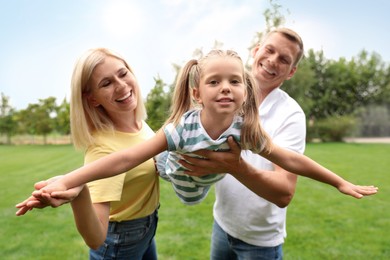 Photo of Cute little girl having fun with her parents in park on summer day