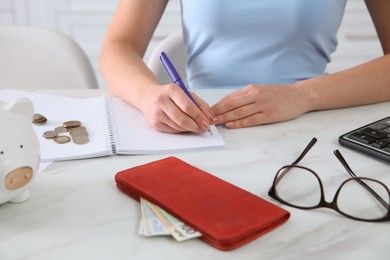 Young woman counting money at table in kitchen, closeup