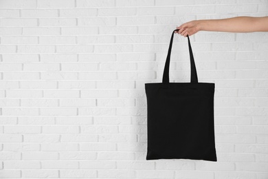 Photo of Woman holding eco bag near brick wall. Mock up for design