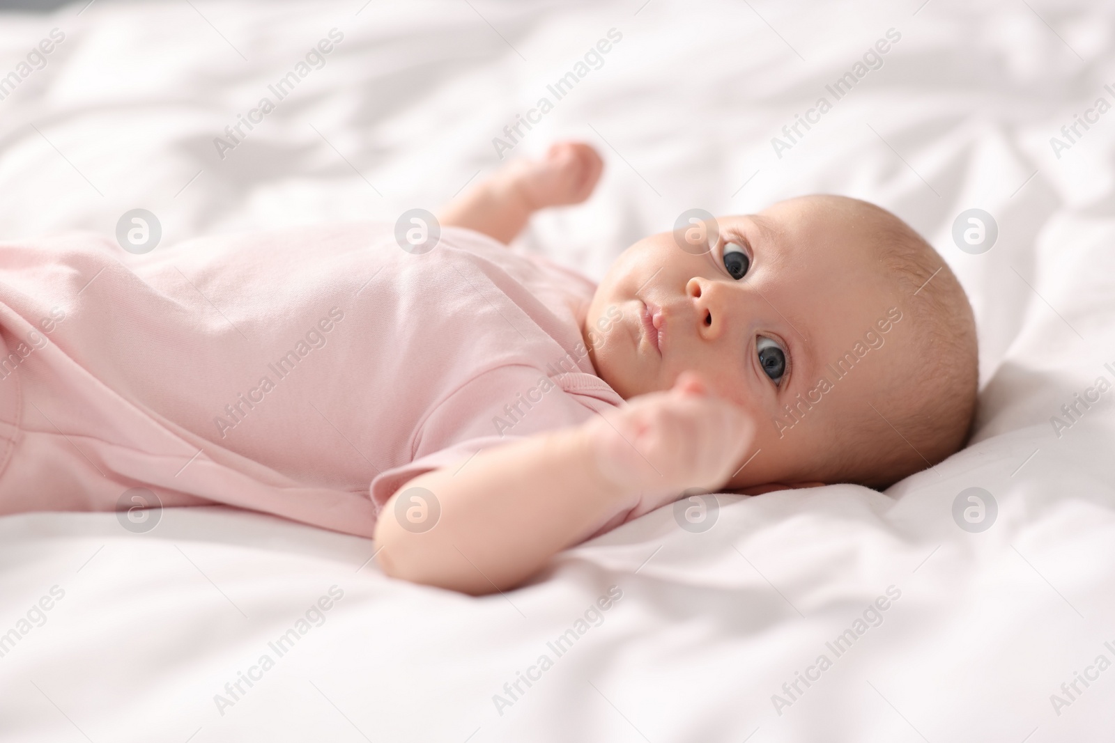 Photo of Cute little baby lying on white sheets