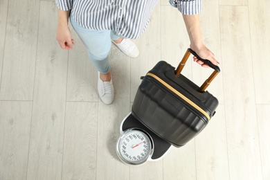 Photo of Woman weighing suitcase indoors, top view. Space for text