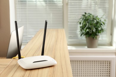 Photo of Modern wi-fi router on wooden counter indoors