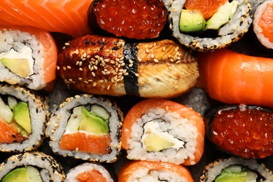 Different tasty sushi rolls as background, top view