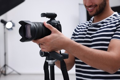 Professional photographer with camera in modern photo studio, closeup
