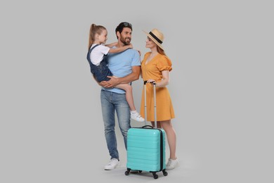 Happy family with turquoise suitcase on light grey background