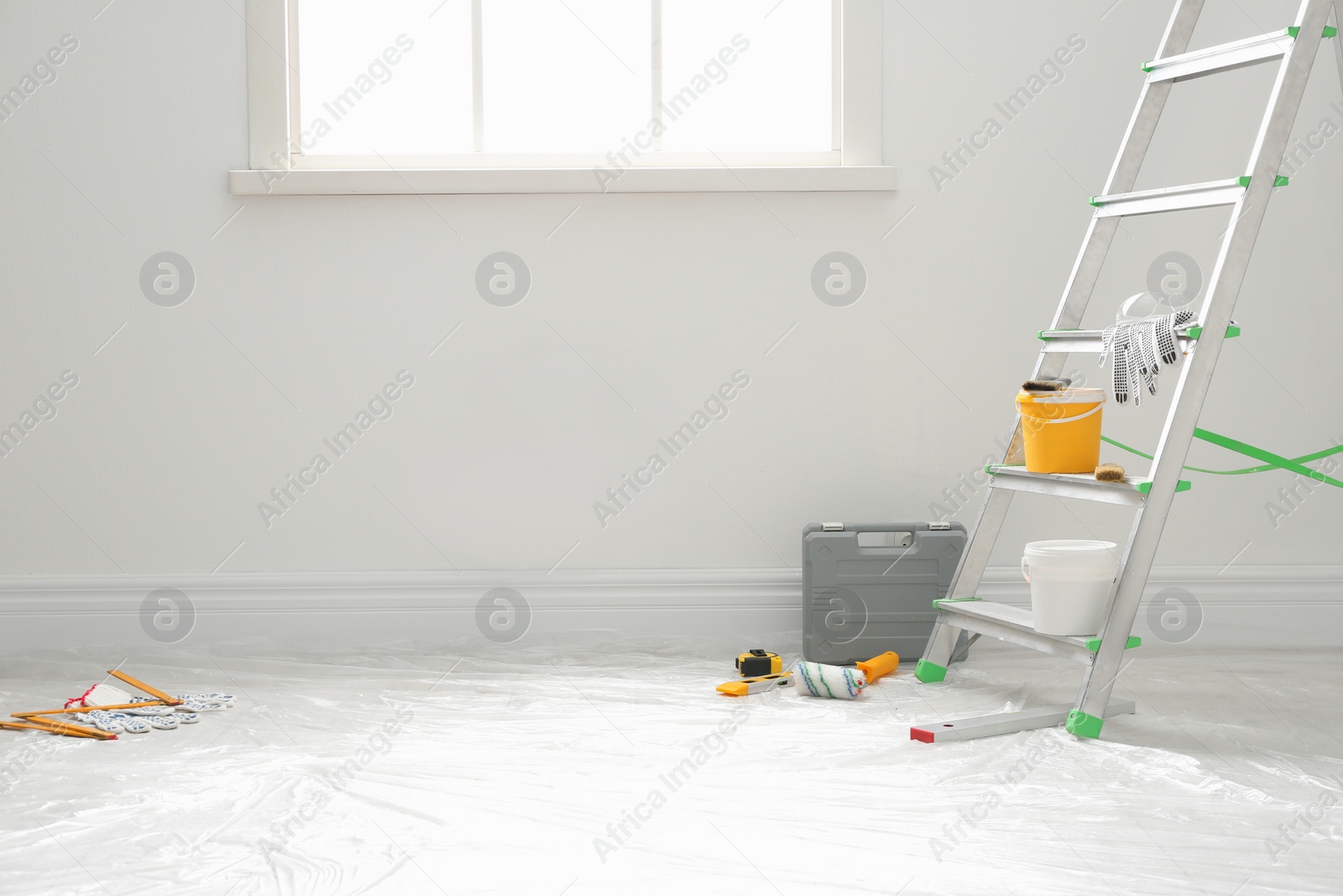 Photo of Stepladder and different tools near wall in room. Interior renovation