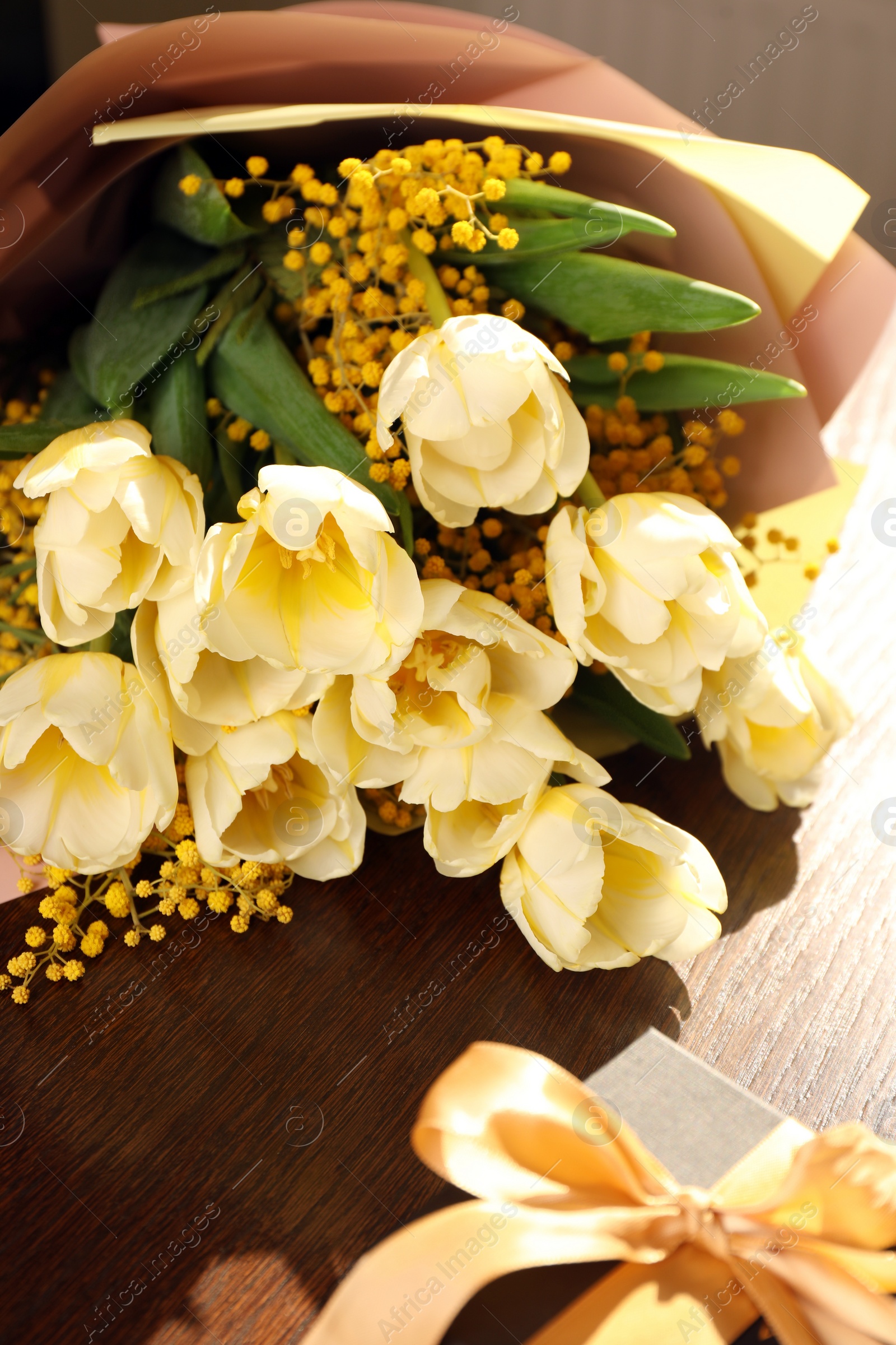 Photo of Bouquet with beautiful tulips, mimosa flowers and gift box on wooden table indoors