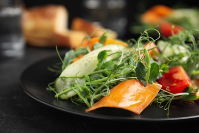 Delicious vegetable salad with microgreen on black table, closeup