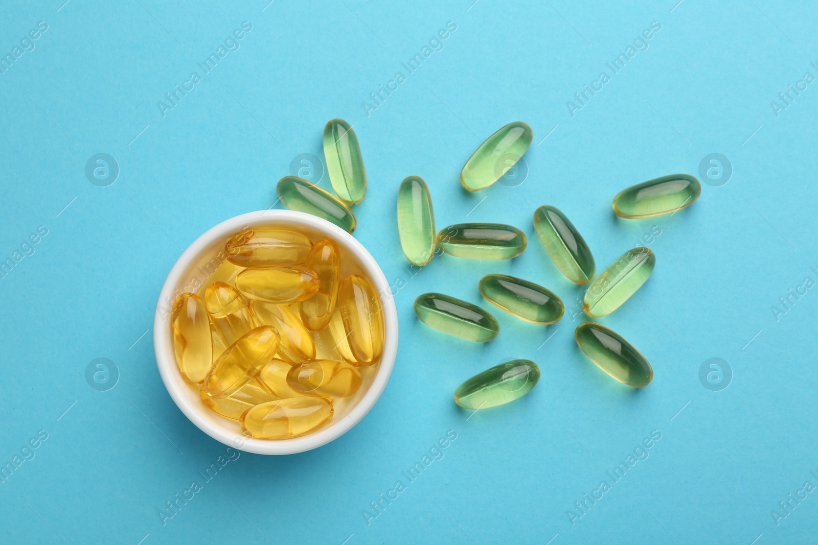 Photo of Vitamin capsules on light blue background, flat lay