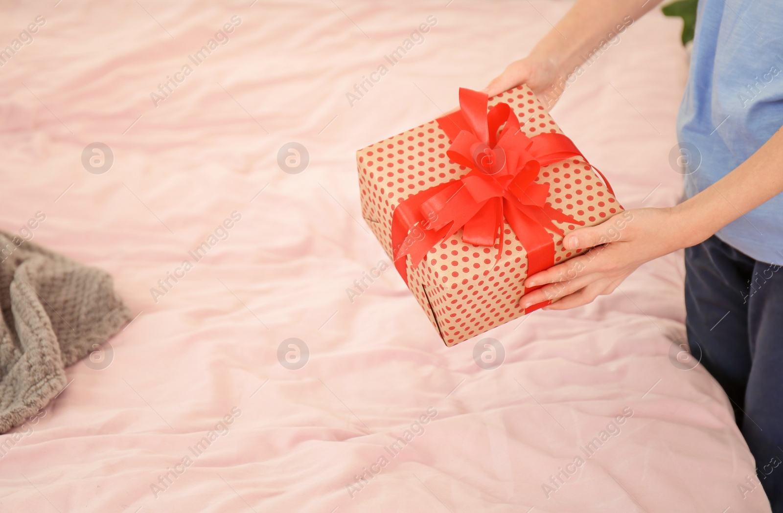 Photo of Little child putting gift box for Mother's Day on bed