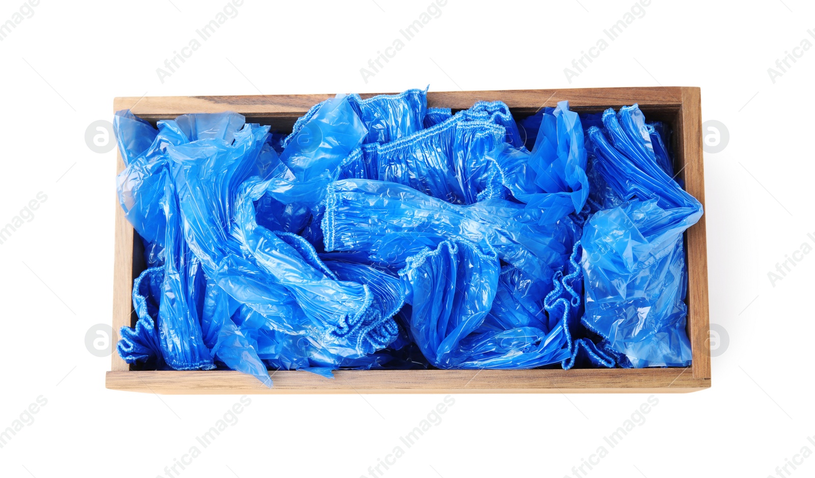Photo of Blue medical shoe covers in wooden crate isolated on white, top view