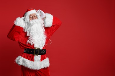 Merry Christmas. Santa Claus in headphones listening to music on red background, space for text