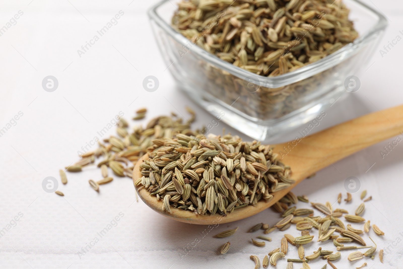 Photo of Bowl and spoon with fennel seeds on white table