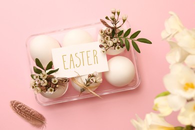 Flat lay composition with chicken eggs, floral decor and word Easter on pink background. Happy celebration