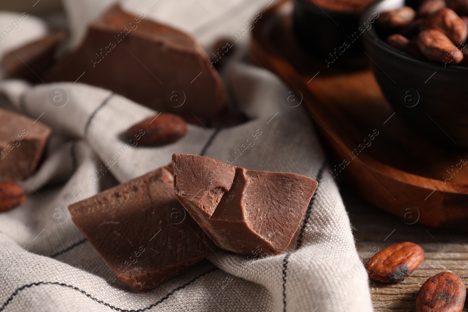 Photo of Pieces of tasty milk chocolate and cocoa beans on table, closeup