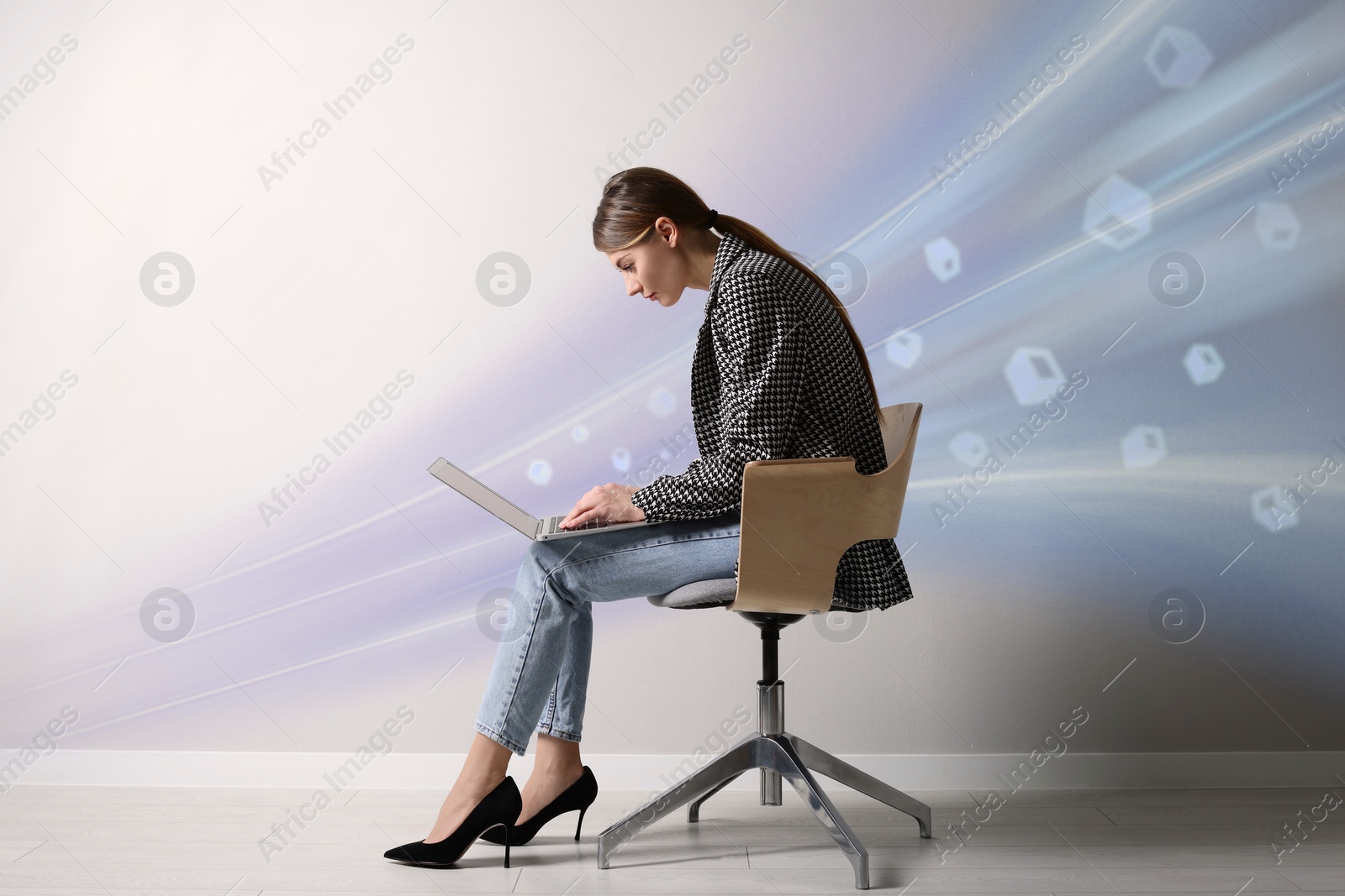 Image of Speed internet. Woman using laptop in chair near light grey wall. Motion blur effect symbolizing fast connection