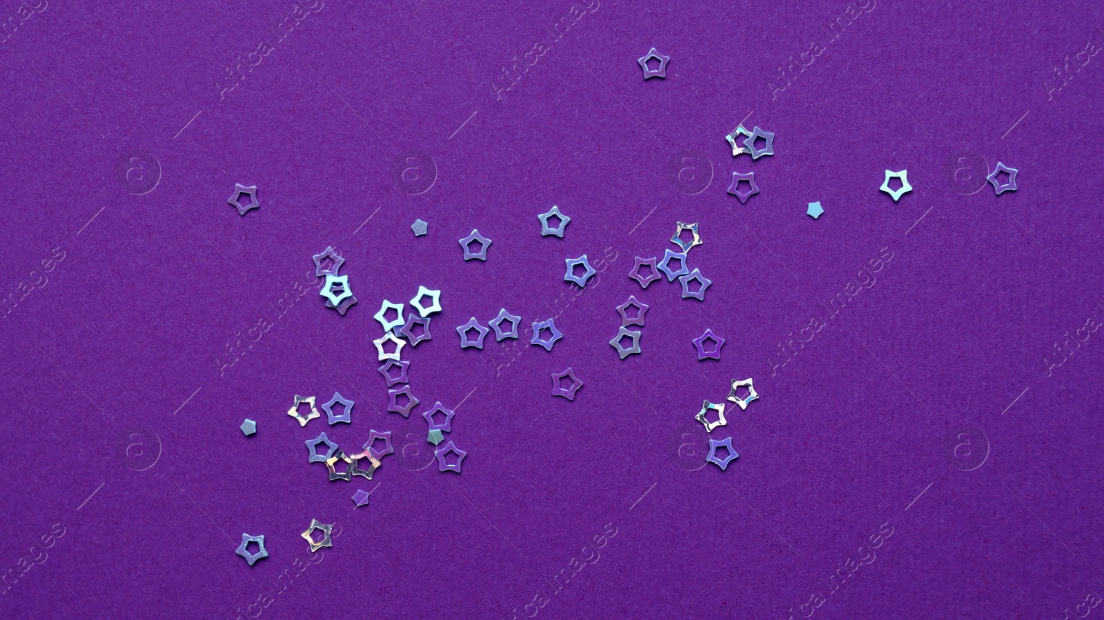 Photo of Many bright star shaped sequins on purple background, flat lay