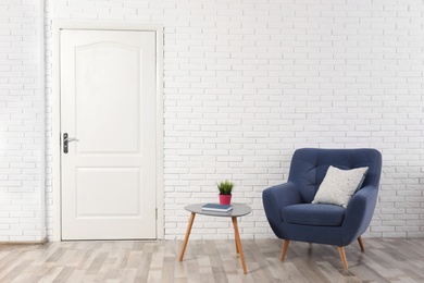 Photo of Light room interior with white door in brick wall