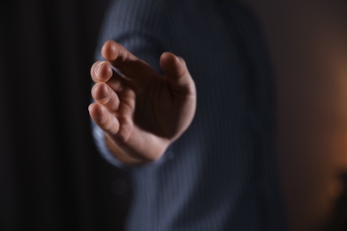 Photo of Man offering helping hand on blurred background, closeup. Space for text