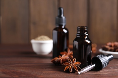 Anise essential oil and spice on wooden table, space for text