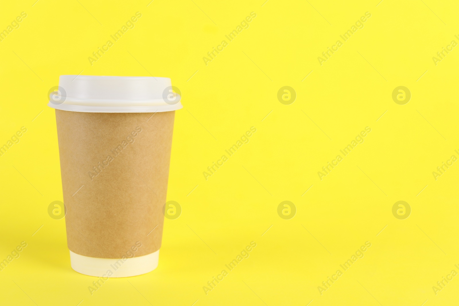 Photo of Paper cup with plastic lid on yellow background, space for text. Coffee to go