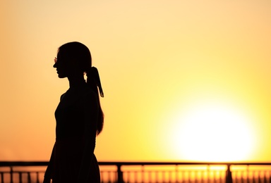 Photo of Silhouette of young woman outdoors at sunset