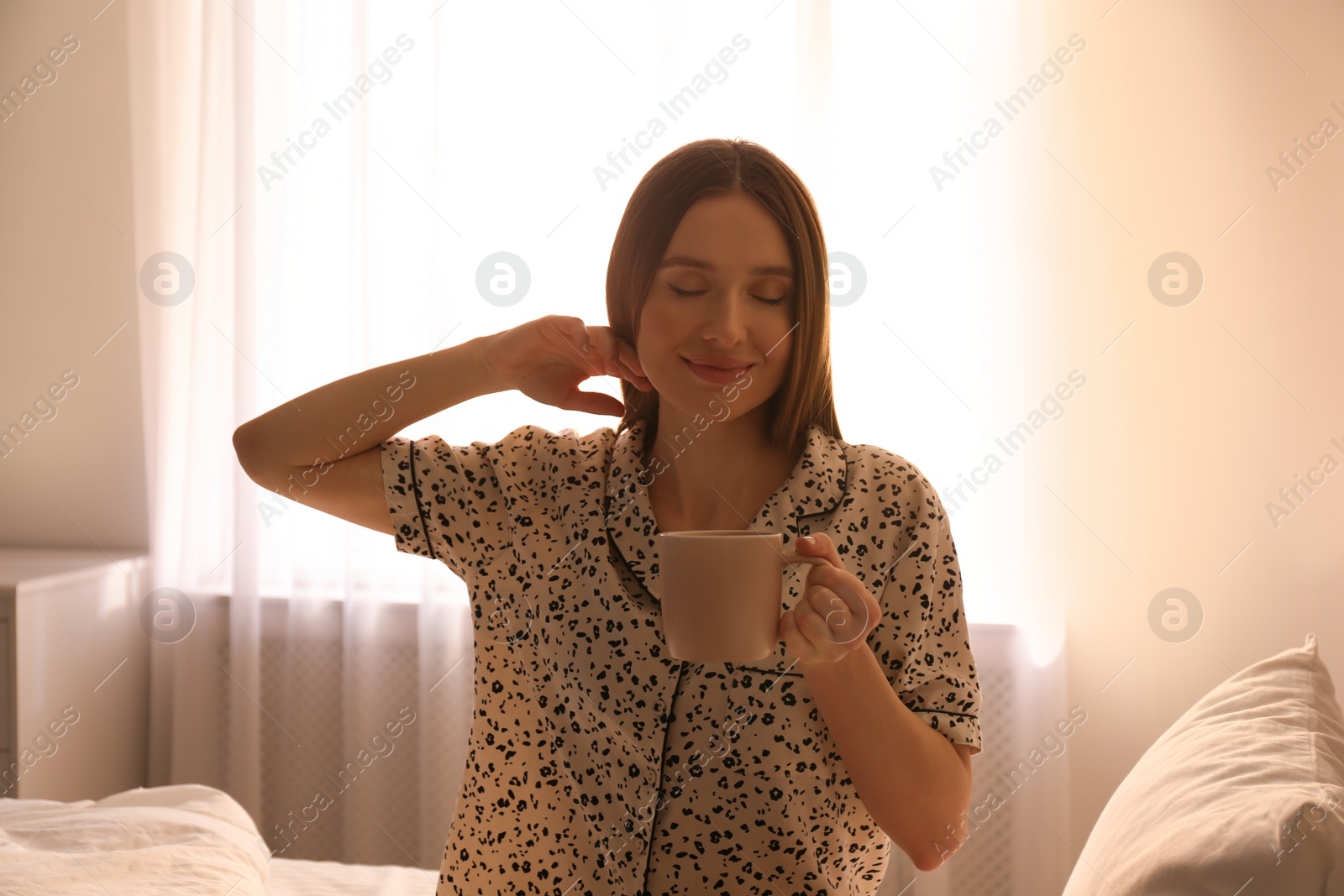 Photo of Young woman with drink on bed at home. Lazy morning