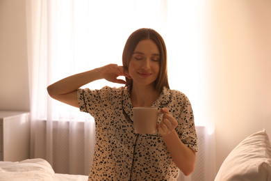 Young woman with drink on bed at home. Lazy morning