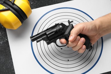 Photo of Man with handgun, shooting target and headphones at table, above view
