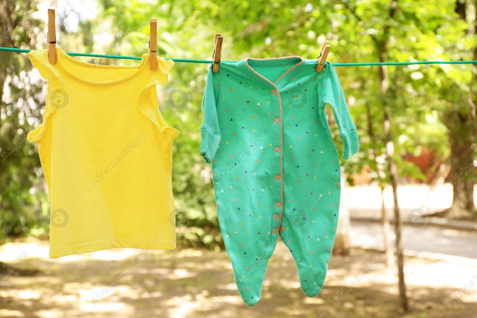 Photo of Laundry line with child's clothes outdoors on sunny day