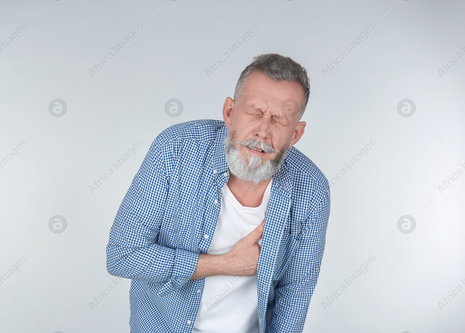 Photo of Man suffering from chest pain on light background