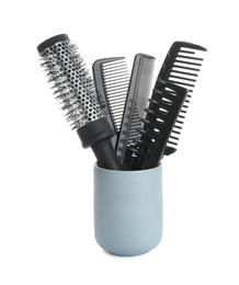 Modern hair brush and different combs in ceramic holder isolated on white