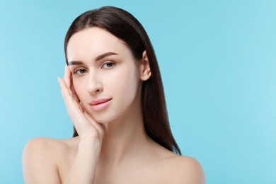 Portrait of beautiful young woman on light blue background. Space for text