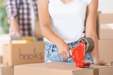 Woman packing box indoors, closeup. Moving day