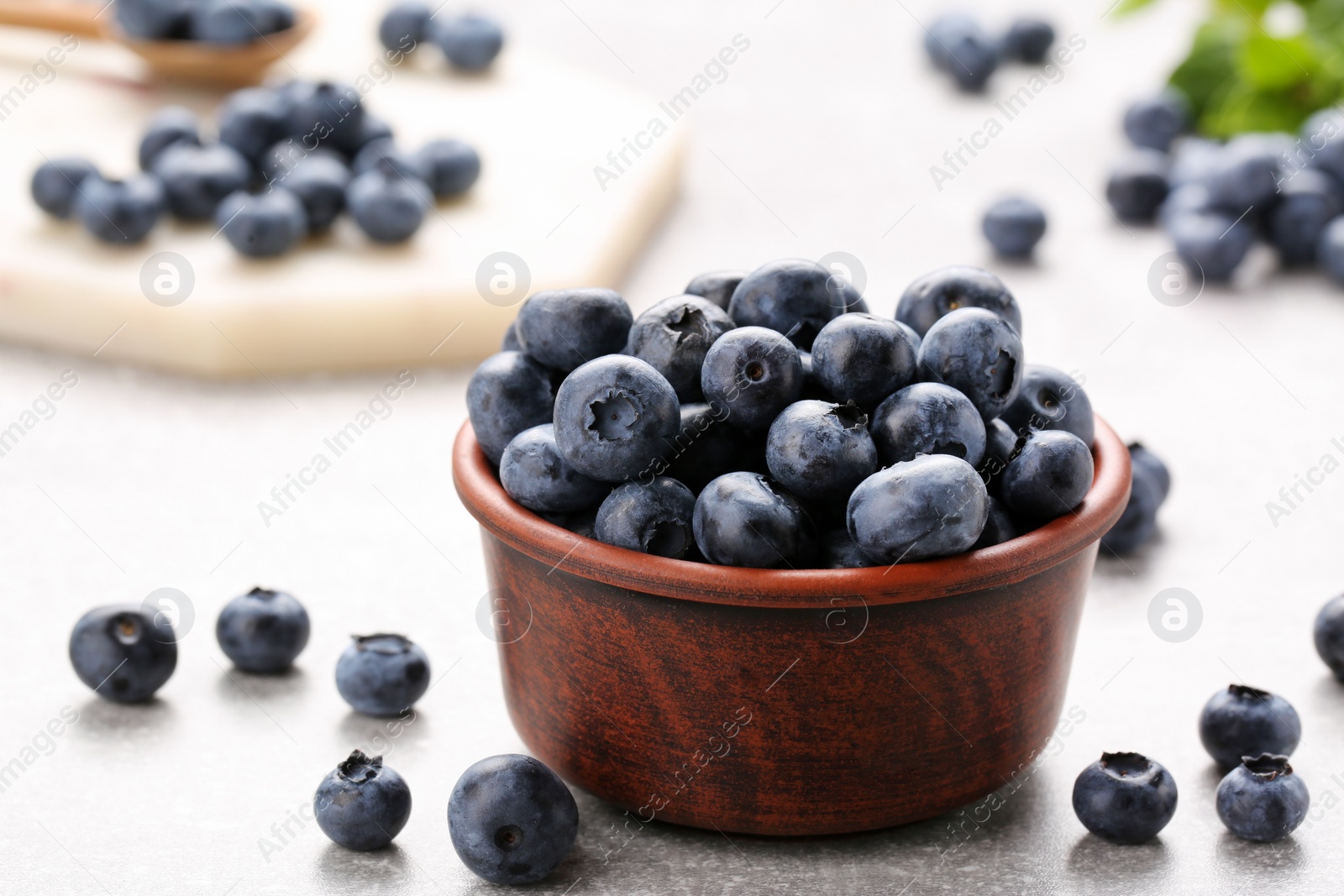 Photo of Tasty fresh blueberries on light grey table, closeup