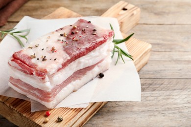 Photo of Tasty salt pork with rosemary and spices on wooden table, closeup. Space for text