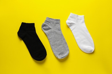 Photo of Different socks on yellow background, flat lay