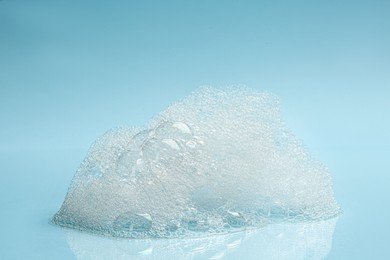 Photo of Drop of fluffy bath foam on turquoise background