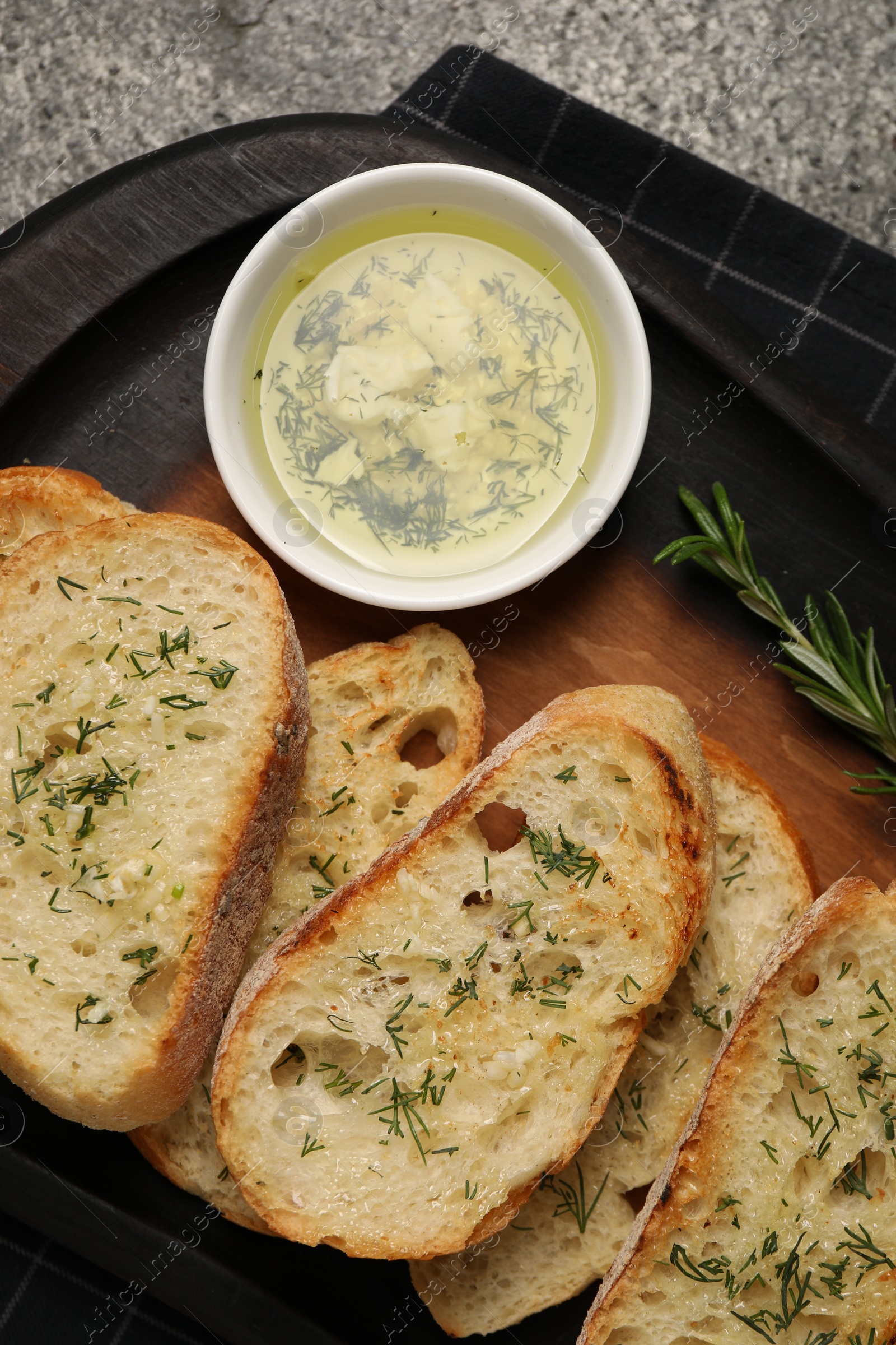 Photo of Tasty baguette with garlic and dill served on grey table, top view