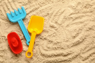 Flat lay of beach toy kit on sand, space for text. Outdoor play