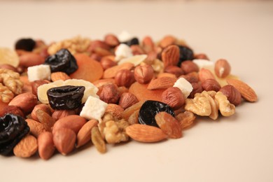 Photo of Different tasty nuts and dried fruits on beige background, closeup