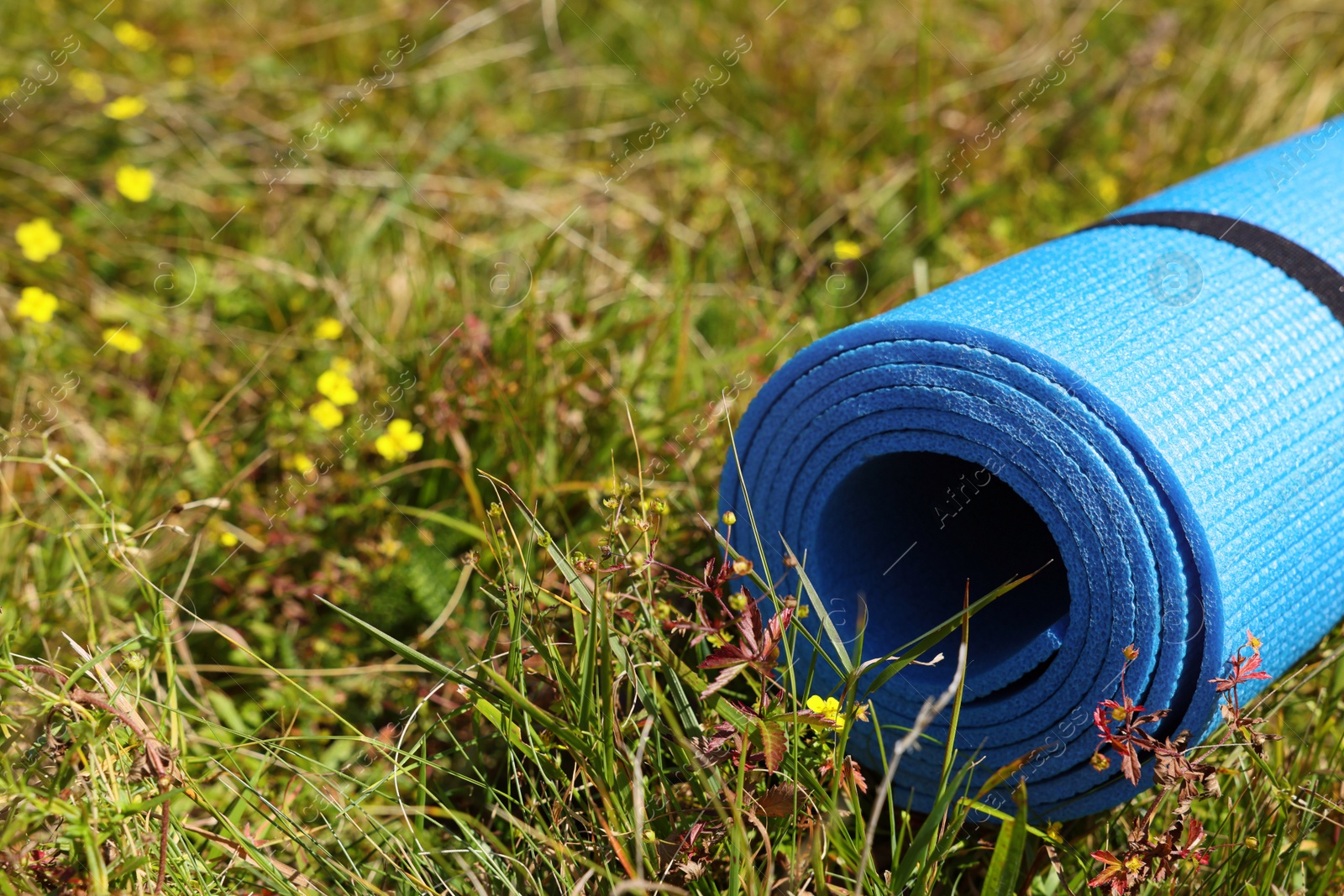 Photo of Rolled blue soft sleeping pad on grass, closeup