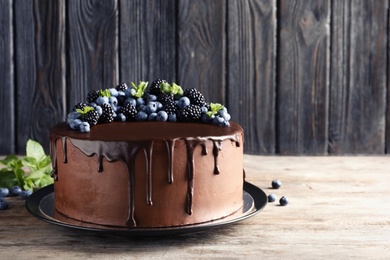 Photo of Fresh delicious homemade chocolate cake with berries on table against wooden background. Space for text