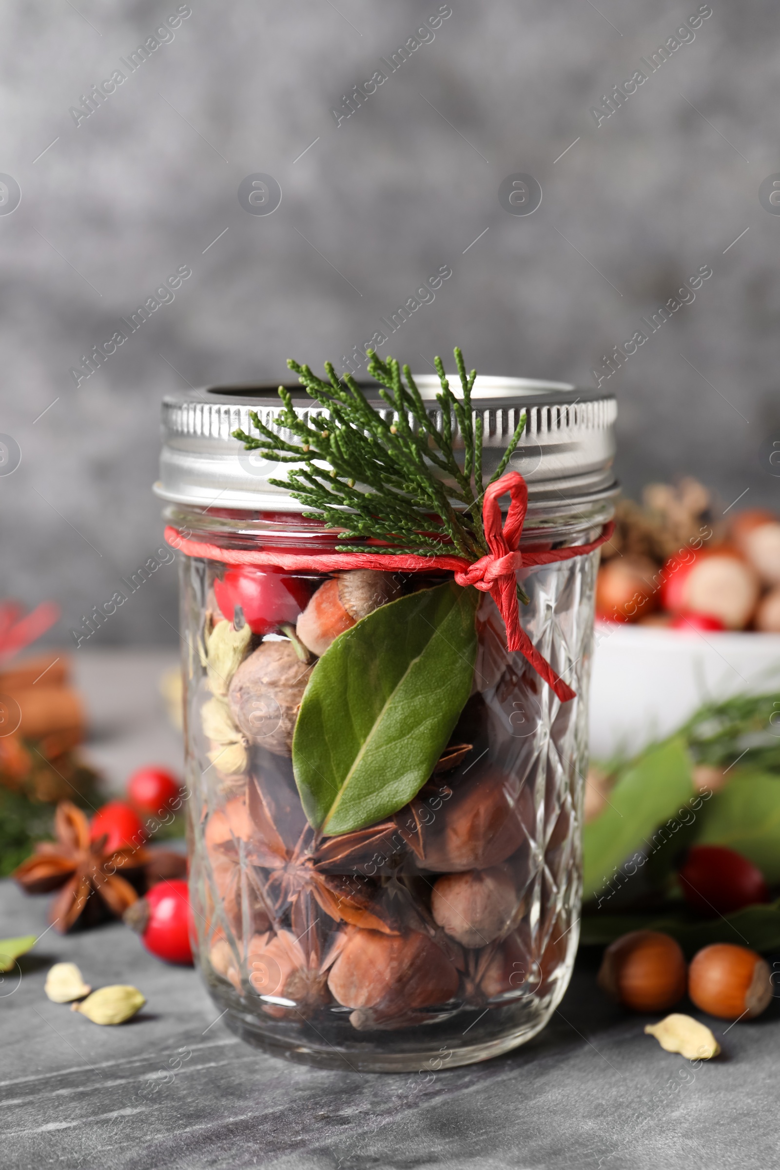 Photo of Aromatic potpourri in glass jar on grey table