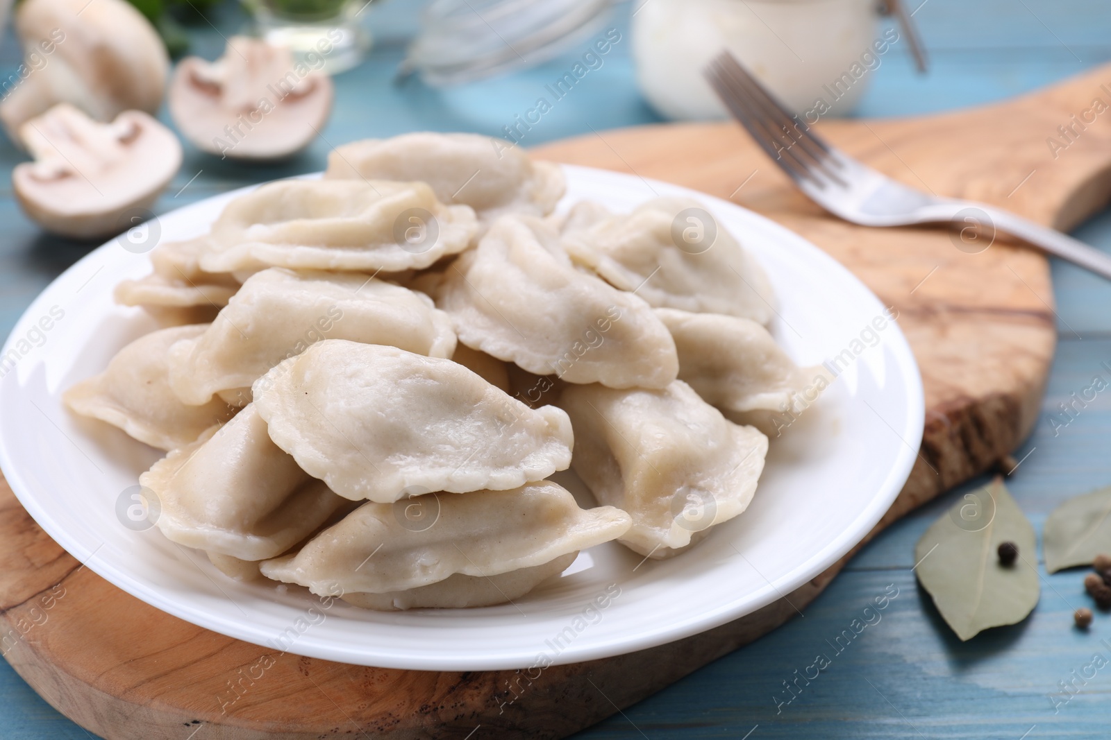Photo of Delicious dumplings (varenyky) with potatoes served on light blue wooden table, closeup