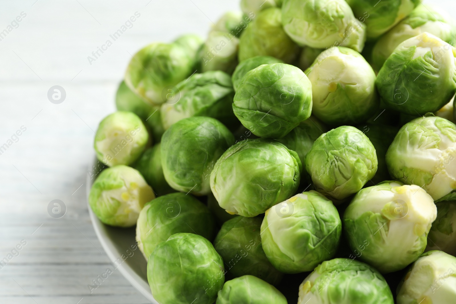 Photo of Plate with fresh Brussels sprouts on wooden background, closeup