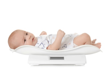 Cute little baby lying on scales against white background