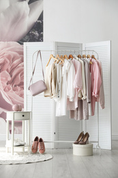 Photo of Rack with stylish women's clothes and handbag indoors. Interior design