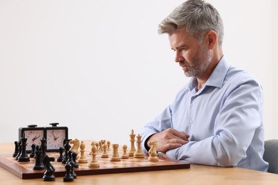 Photo of Man playing chess during tournament at table against white background